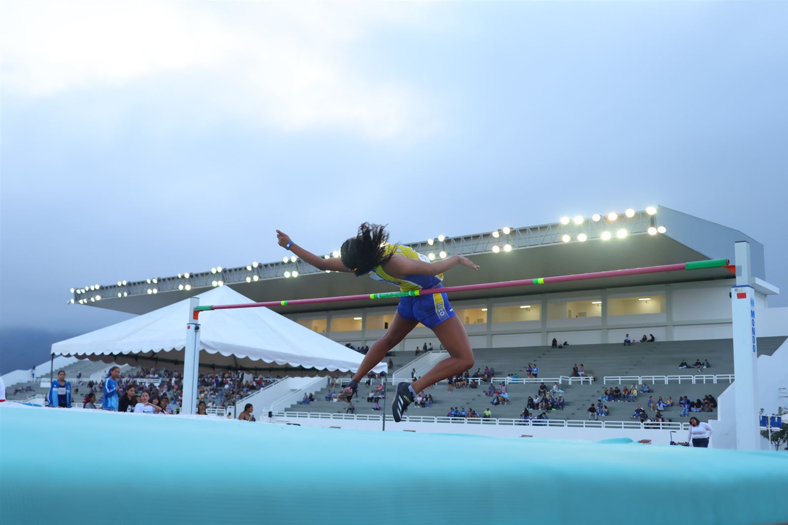 Atleta de salto de altura al atardecer en estadio